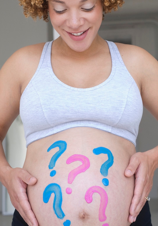Pregnant African woman with question marks painted on belly