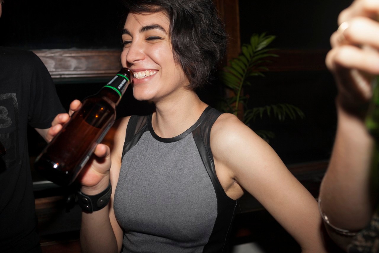 16 Aug 2014 --- Young woman enjoying a beer at a party --- Image by © HEX/Corbis