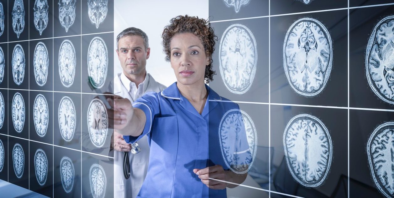 Doctor and nurse working with MRI brain scans seen through interactive display --- Image by © Monty Rakusen/Corbis