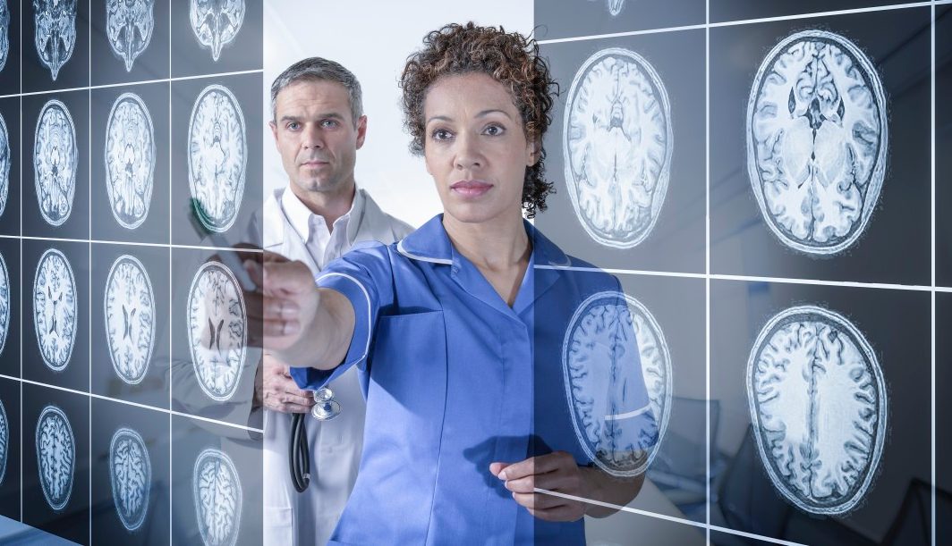 Doctor and nurse working with MRI brain scans seen through interactive display --- Image by © Monty Rakusen/Corbis