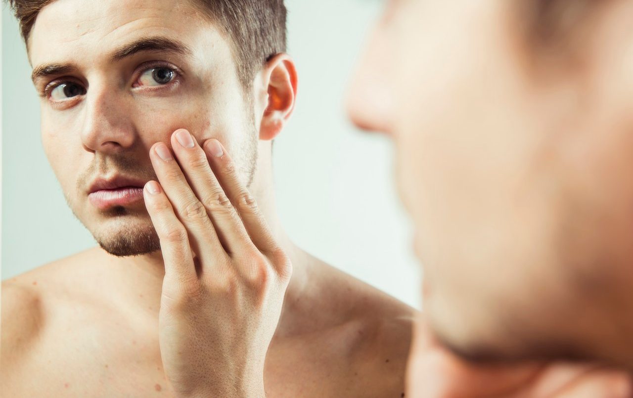 Close-up of young man looking at reflection in bathroom mirror, studio shot --- Image by © Radius Images/Corbis