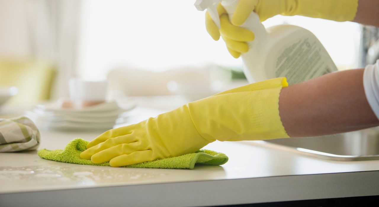 04 Oct 2012 --- Woman in rubber gloves using spray cleaner on counter. --- Image by © Hero Images/Corbis