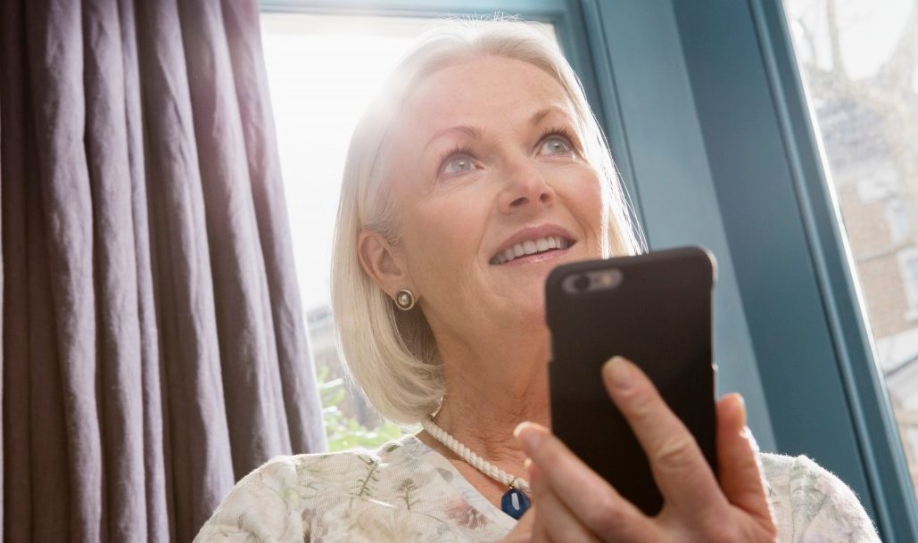 Woman sitting on sofa using smartphone --- Image by © Corbis