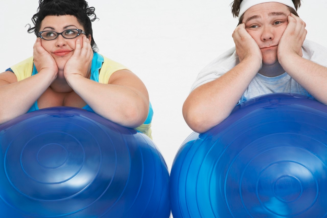 Disinterested overweight man and woman lying on Exercise Balls close up --- Image by © Mike Watson/moodboard/Corbis
