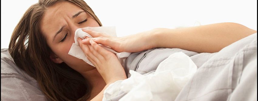 Young woman lying in bed blowing nose --- Image by Â© Mike Kemp/Tetra Images/Corbis