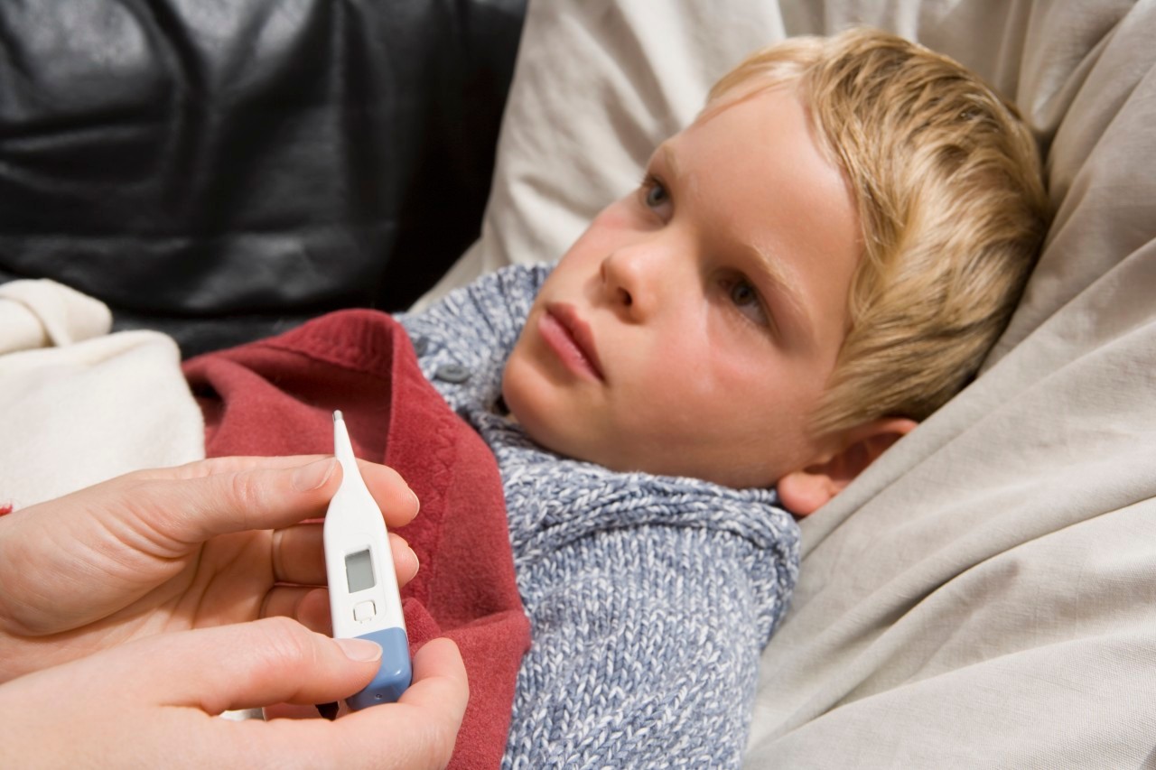 Sick child lying on back with digital thermometer --- Image by © Andreas Schlegel/fstop/Corbis