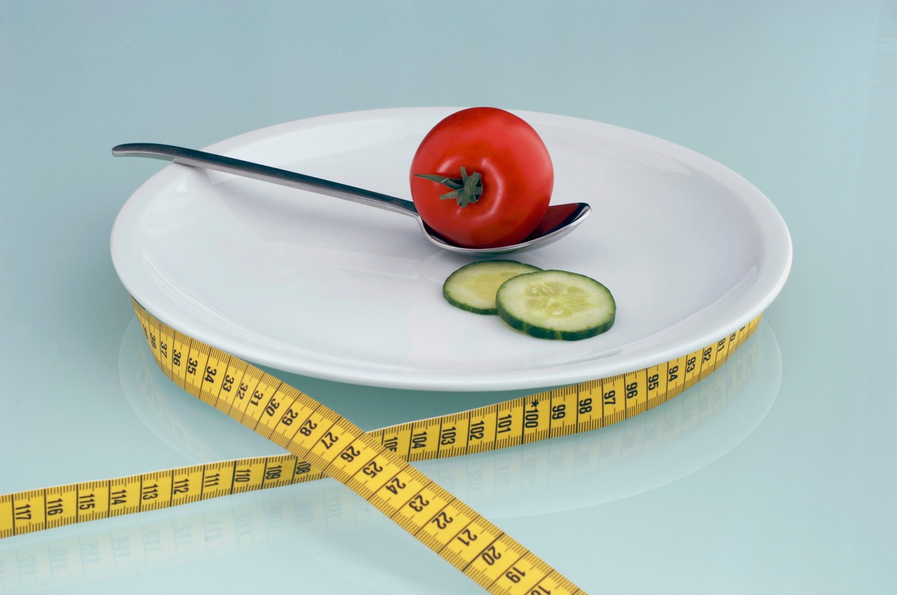 Tomato and cucumber slice on plate with measuring tape, close-up --- Image by © Achim Sass/Westend61/Corbis