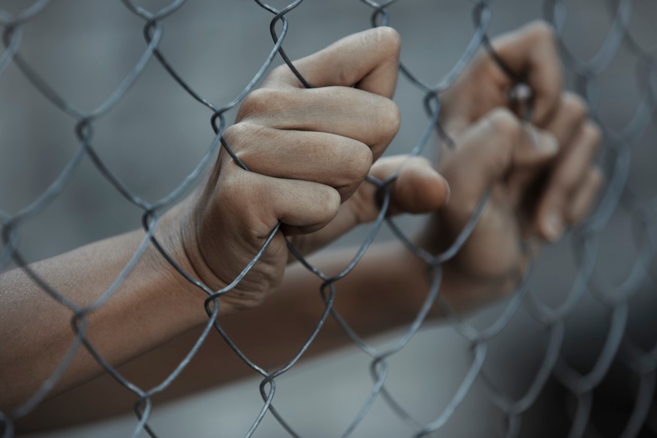 07 Sep 2014 --- Hands of prisoner behind chain link fence --- Image by © Arman Zhenikeyev/Corbis