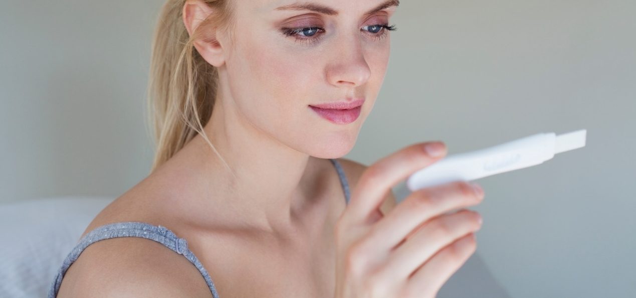 Young woman looking at pregnancy test --- Image by © Sydney Bourne/Image Source/Corbis