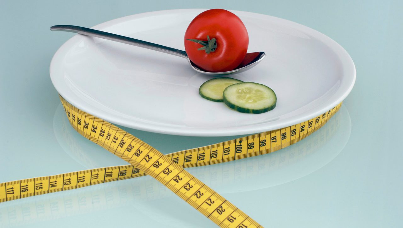 Tomato and cucumber slice on plate with measuring tape, close-up --- Image by © Achim Sass/Westend61/Corbis