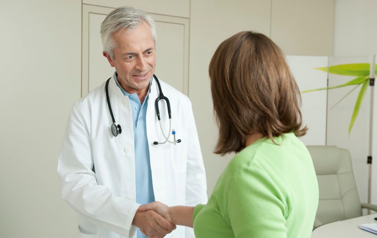 Doctor and female patient shaking hands --- Image by © Petrol/Corbis