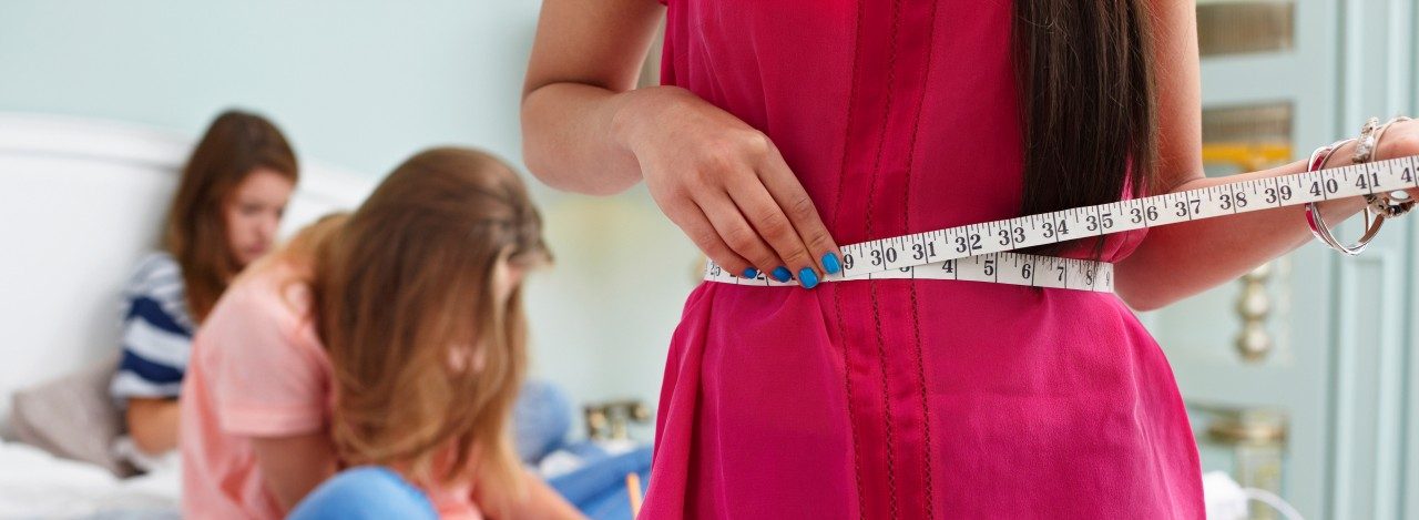 Teenage girl measuring her waist --- Image by © Sverre Haugland/Image Source/Corbis