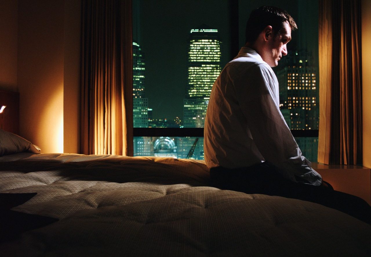 Serious Looking Man Sitting on Bed --- Image by © Image Source/Corbis