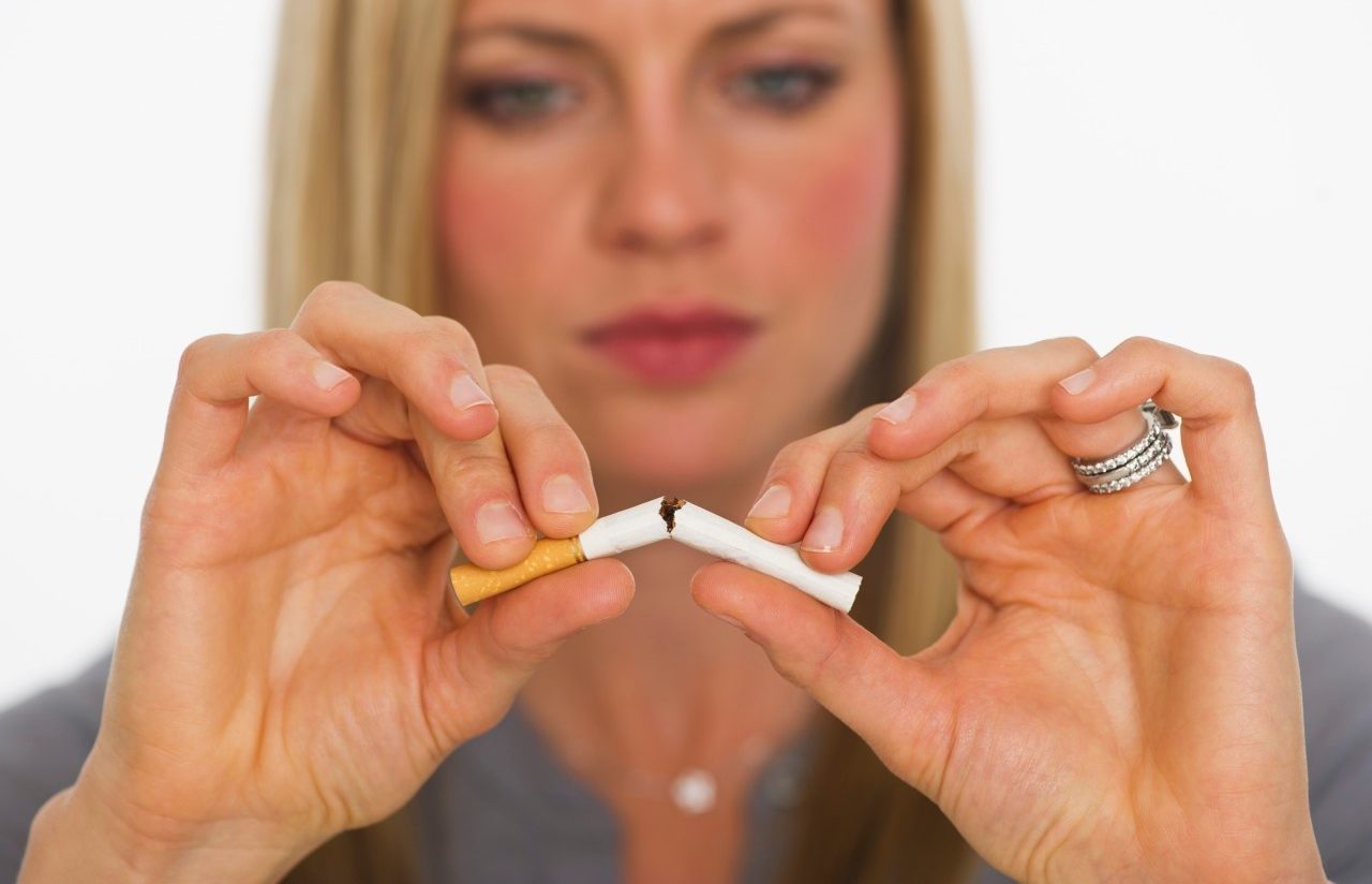 Young woman breaking cigarette --- Image by © Tetra Images/Corbis