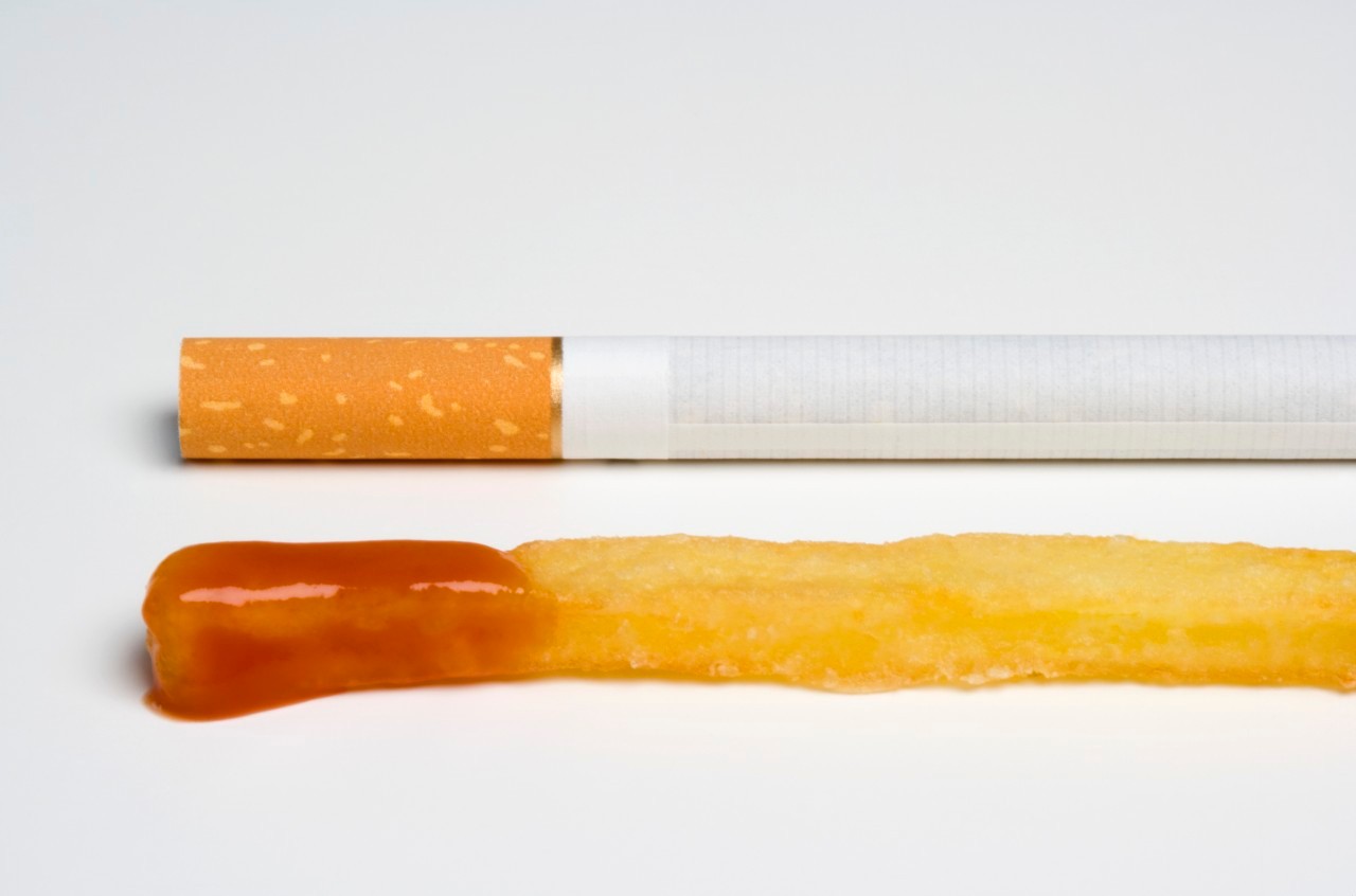 Cigarette Next to French Fry with Ketchup --- Image by © Martin Diebel/fstop/Corbis