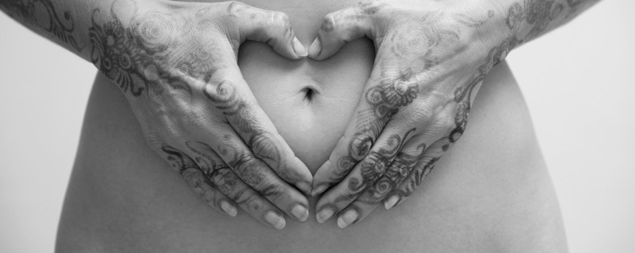 Close-up of Woman with Henna on Hands, Hands in Heart-shape around Belly Button, Studio Shot --- Image by © Radius Images/Corbis