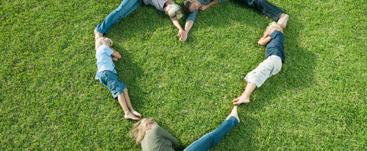 People lying on grass positioned in shape of heart --- Image by © Milena Boniek/PhotoAlto/Corbis