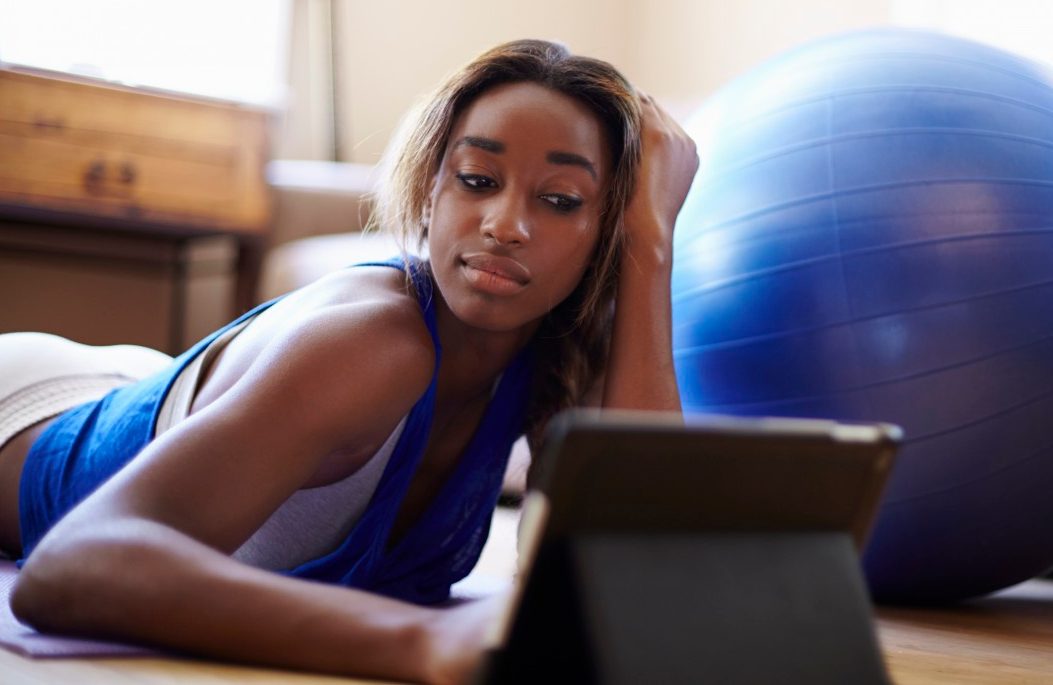 27 Jun 2014 --- Young woman taking a training break, using digital tablet in sitting room --- Image by © Kevin Kozicki/Image Source/Corbis