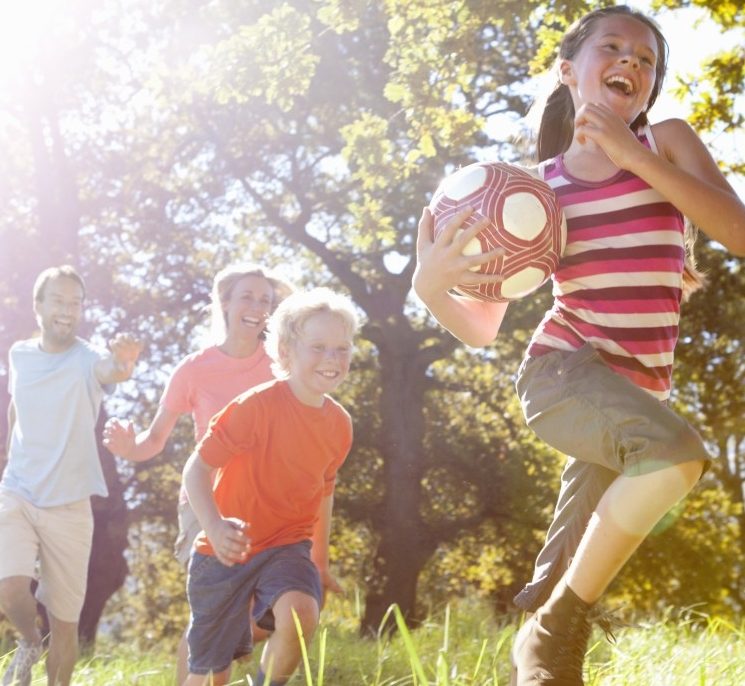 16 Sep 2014 --- Grandparents and grandchildren running with ball in rural field --- Image by © Ian Lishman/Juice Images/Corbis