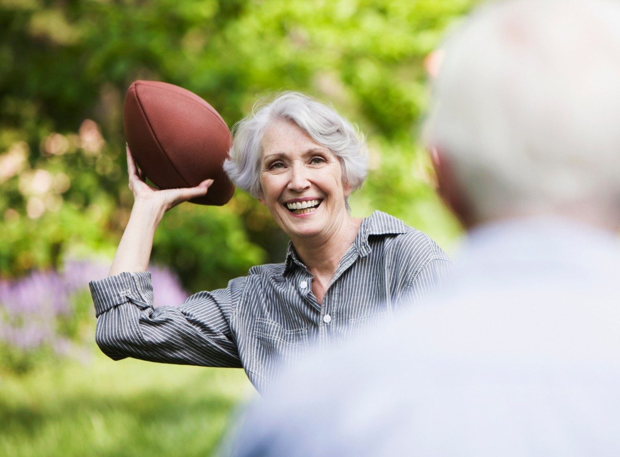 Senior woman throwing football to partner --- Image by © JOSE LUIS PELAEZ, INC./Image Source/Corbis