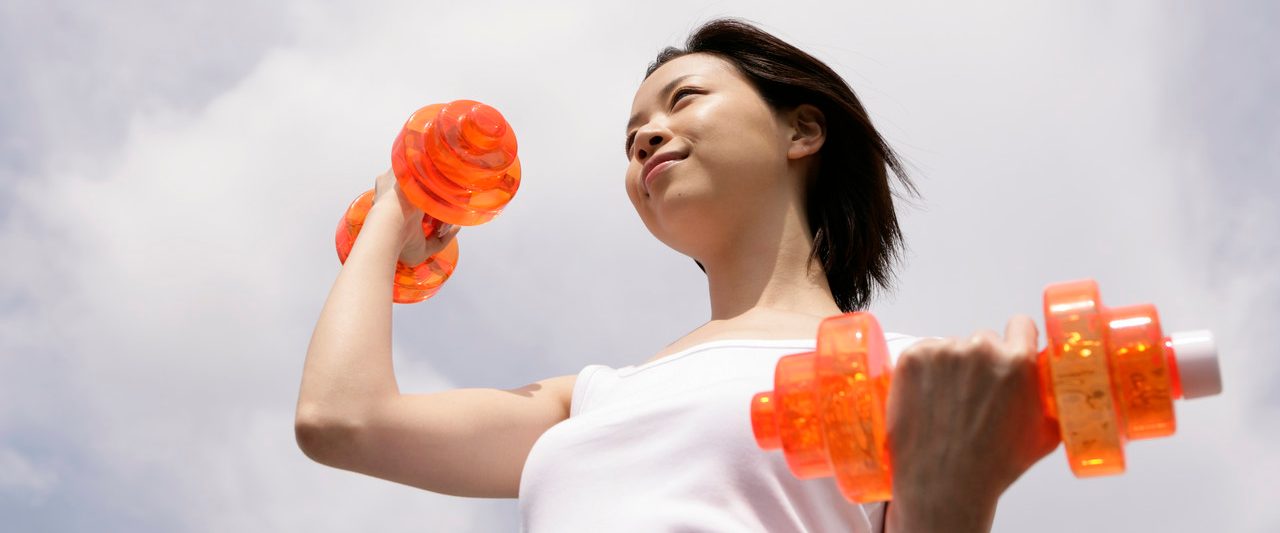 A woman exercising as she lifts up the dumbbells --- Image by © Image Werks/Corbis
