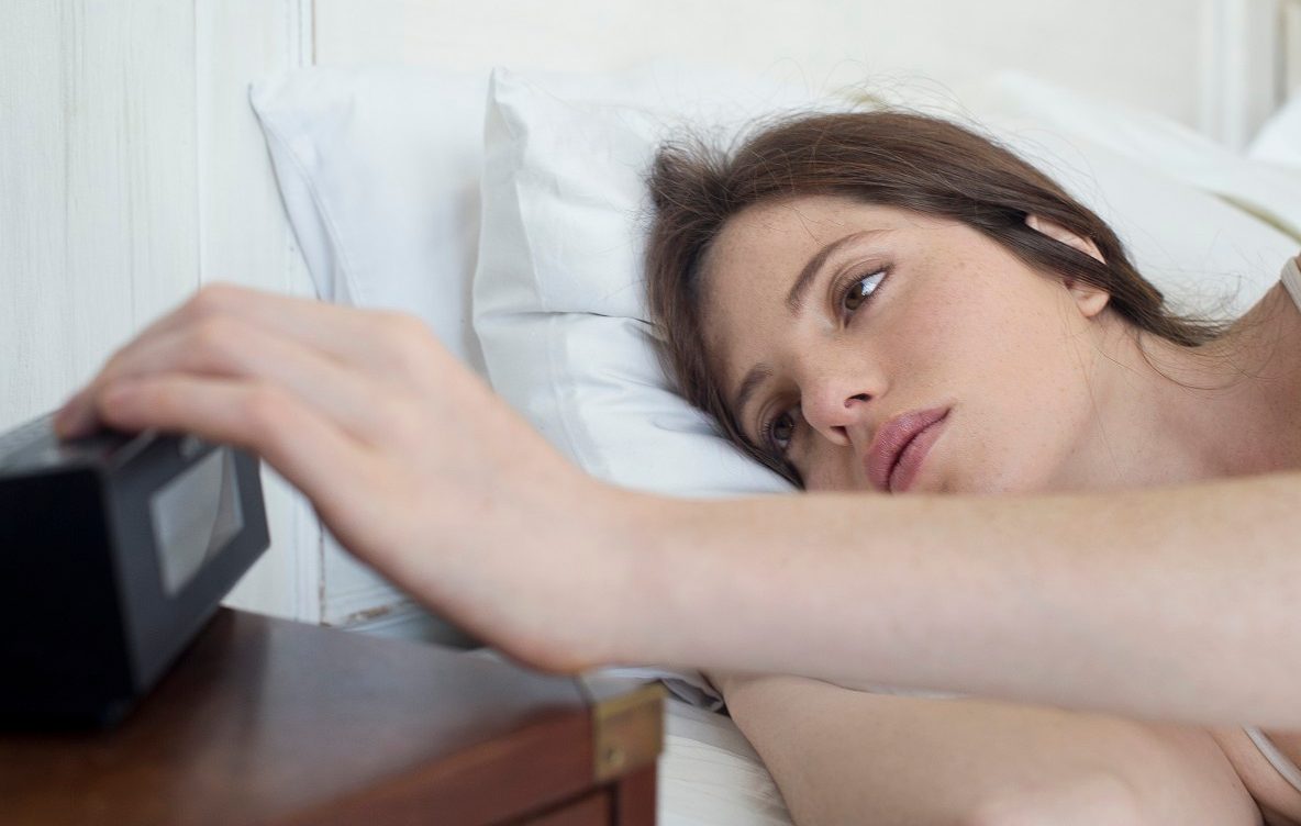18 Feb 2014 --- Woman in bed pressing alarm clock snooze button --- Image by © Frederic Cirou/PhotoAlto/Corbis